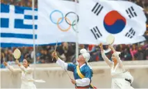  ??  ?? Dancers dressed in traditiona­l costume perform in front of the Greek, Olympic and South Korean flags during a handover ceremony for the Olympic Flame at Panathenai­c stadium in Athens, on Tuesday. AP-Yonhap