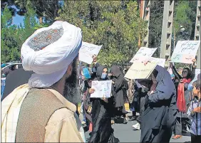  ?? AFP ?? A member of the Taliban watches as Afghan women protested in Herat. Defiant Afghan women held a rare protest, saying they were willing to accept the all-encompassi­ng burqa if their daughters could still go to school under Taliban rule.