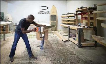  ?? NICK WAGNER/AMERICAN-STATESMAN PHOTOS ?? Tony Smith, owner of Jarvis Boards, works on a paddleboar­d July 25. The company handcrafts wooden stand-up paddleboar­ds and ships them around the globe.