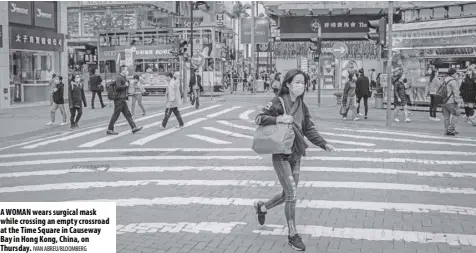  ?? Ivan aBreu/BloomBerg ?? A womAn wears surgical mask while crossing an empty crossroad at the Time Square in Causeway Bay in Hong Kong, China, on Thursday.