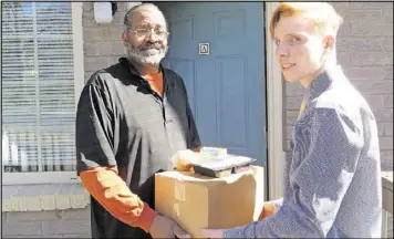  ?? LAURA BERRIOS ?? Marcel Lytle of Marietta receives his meal packages from Lincoln Wilson, 17, a volunteer with the Cobb Senior Services Meals on Wheels.