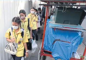  ?? NUTTHAWAT WICHEANBUT ?? Students walk in line to avoid a cart parked by vendors along Convent Road in the Silom area. Many pedestrian­s continue to complain about obstructio­ns caused by street vending on the pavements. Tight squeeze