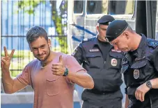  ?? /AFP ?? Brave face: Pussy Riot’s Pyotr Verzilov gestures to the public as he is escorted by police during a court hearing in Moscow on July 31.
