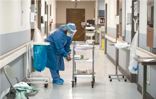  ?? ASHLEE REZIN GARCIA/SUN-TIMES FILE PHOTO ?? Nurse Jeanette Averett delivers dinner trays in the COVID-19 unit at Roseland Community Hospital on the Far South Side in April.