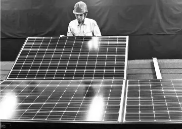  ??  ?? A Panasonic employee inspects a photovolta­ic solar panel at the company’s Eco Solutions manufactur­ing plant in Ishiyama, Shiga Prefecture, Japan.