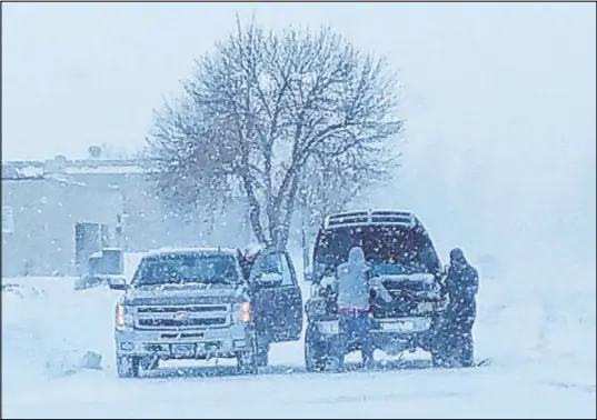  ?? Jim Monk The Associated Press ?? Residents in Fargo, N.D., attempt to jump-start a vehicle with a dead battery in the middle of a snowstorm on Saturday. A blizzard warning was issued until Saturday evening for parts of North Dakota, South Dakota, Minnesota and Iowa.