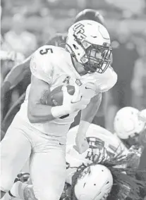  ?? EASLEY/AP TIMOTHY D. ?? UCF running back Isaiah Bowser (5), who had his production hampered by a knee injury, attempts to get past an oncoming rush by Louisville Cardinals safety Shavarick Williams during the first half Friday night.