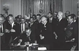  ?? FILE ?? President Lyndon Johnson signs the Civil Rights Act, bipartisan legislatio­n that protected against discrimina­tion based on race, color, religion, sex and nationalit­y on July 2, 1964.