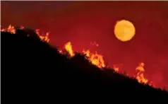  ?? MIKE ELIASON/SANTA BARBARA COUNTY FIRE DEPARTMENT VIA AP ?? The moon rises as the Alamo Fire in Santa Barbara County, Calif., burns on a hilltop.