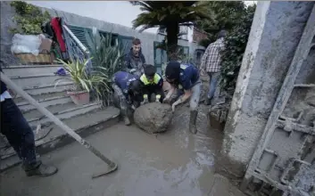  ?? Associated Press ?? People remove mud and debris Sunday after heavy rainfall triggered landslides that collapsed buildings and killed at least seven in Casamiccio­la, on the southern Italian island of Ischia.