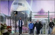  ?? ELAINE THOMPSON — THE ASSOCIATED PRESS ?? Boeing workers exit the plant in front of a giant mural of a jet on the side of the manufactur­ing building Monday in Renton, Wash.