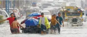  ?? AP FOTO ?? MONSOON. Heavy rain causes flooding in Metro Manila. Volunteers try to ferry commuters to safer corners of the streets.