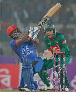  ?? AP ?? Mohammad Shahzad plays a shot as Bangladesh’s Mushfiqur Rahim looks on in Dhaka. —