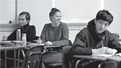  ?? AP Photo/Elaine Thompson ?? ■ Senior Hazel Ostrowski, center, smiles as she looks up during her first period, AP statistics class at Franklin High School on Wednesday in Seattle. High school students are getting more sleep in Seattle, according to a study on later school start times. Ostrowski was among a group at Franklin and another Seattle high school who wore activity monitors to discover whether a later start to the school day would help them get more sleep. It did, adding 34 minutes of slumber a night, and they reported less daytime sleepiness and grades improved.