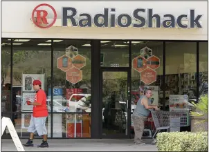  ?? (AP) ?? People pass a RadioShack store in Orlando, Fla., in 2014. Investors in the defunct RadioShack brand plan to revive it as a competitiv­e online business.