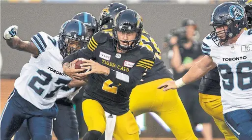 ?? PETER POWER/THE CANADIAN PRESS ?? Johnny Manziel, making his CFL debut, finds daylight under pressure from Argos defensive back Jonathan Dowling, left, in Friday night’s game at Tim Hortons Field.
