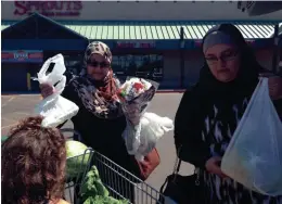  ?? KAYLA KING-SUMNER/THE REPUBLIC ?? Kristy Shabbah of the Islamic Center of the East Valley and her family pack groceries and flowers for the refugee family into her van.