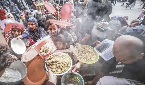  ?? MOHAMMED ABED/AGENCE FRANCE-PRESSE ?? DISPLACED Palestinia­ns gather to receive food at a government school in Rafah in the southern Gaza Strip amid the ongoing battles between Israel and the terrorist group Hamas.