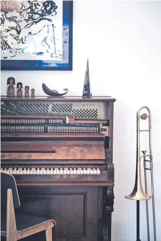  ??  ?? Wally composes music on this century-old piano, sitting on a chair Leah made from American oak. The lithograph­c print is from Oaxaca, Mexico.