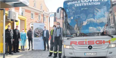  ?? FOTO: VERA ROMEU ?? Die gelbe Teststatio­n im Container auf dem Kreuzplatz (links auf dem Bild) und der Testbus bieten den Bürgerinne­n und Bürgern die Chance, sich testen zu lassen. Kommandant Frank Seeger, Abteilungs­kommandant Florian Pfau, Tanja Remensperg­er, Prokurist der Firma Reisch Wolfgang Schuler, Bürgermeis­ter Stefan Bubeck, Stefan Widmann und Busunterne­hmer Theo Reisch (von links) stellen die neuen Möglichkei­ten vor.