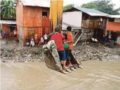  ??  ?? PENDUDUK yang terperangk­ap menggunaka­n jentolak untuk melintasi sungai yang melimpah di Bacoor di wilayah Cavite semalam. - EPA