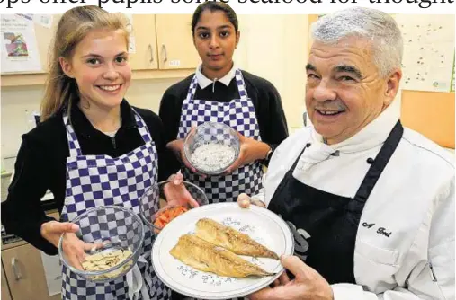  ??  ?? FISH DISH: Highland chef Alan Frost at Millburn Academy with his 14-year-old assistants Megan Keith, left, and Ruhi Mahomoodal­ly