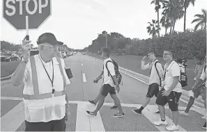  ??  ?? School crossing guard Tony Sorrentino helps students as they head to Marjory Stoneman Douglas High School on Wednesday to begin a new academic year.