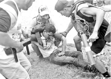  ?? — AFP photo ?? Anti-government protesters help an injured partner during clashes within the “Marcha de las Flores” in Managua.