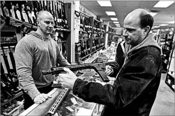  ?? KEITH SRAKOCIC/AP ?? Wes Morosky, owner of Duke’s Sport Shop. left, helps Ron Detka shop for a rifle Friday at his store in New Castle, Pa.