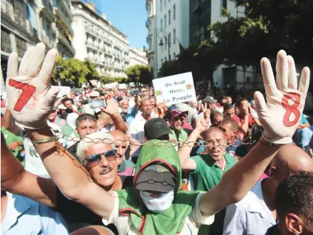  ?? Reuters ?? A protester raises chained hands during a rally demanding social and economic reforms, as well as the departure of the ruling elite in Algiers on Tuesday.