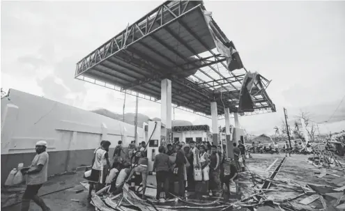  ?? PHOTOS BY FRANCIS R. MALASIG, EUROPEAN PRESSPHOTO AGENCY ?? Filipinos take gas from a station Wednesday in Tacloban. Although supplies have arrived, they can’t be transporte­d to the worst- hit areas.