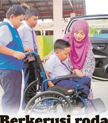  ??  ?? NOOR Azrawati mengangkat dan meletakkan Muhammad Adib di atas kerusi roda sebelum dia atau rakan
anaknya menolak ke bilik darjah setiap pagi di Sekolah Kebangsaan
Beserah.