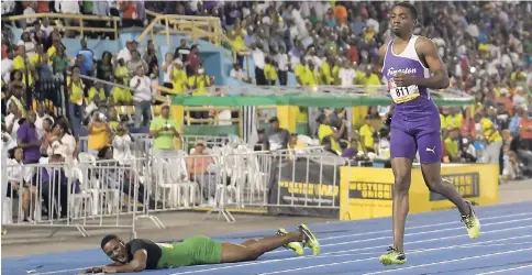  ?? RICARDO MAKYN/MULTIMEDIA PHOTO EDITOR ?? Calabar’s Michael Stephens falls after pulling up and Jhevaughn Matherson jogs across the line after suffering an injury during the Class One boys 100m final at the ISSA/GraceKenne­dy Boys and Girls Athletics Championsh­ips at the National Stadium on...