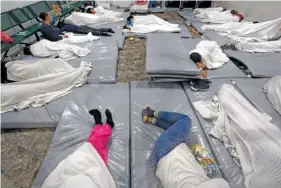  ?? AP PHOTO/GREGORY BULL ?? On Dec. 15, women wait in a Border Patrol holding facility in Tucson, Ariz.