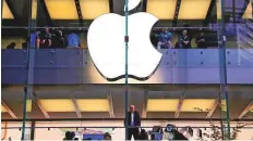  ?? Reuters ?? A customer stands underneath an illuminate­d Apple logo as he looks out the window of the Apple store in Sydney.