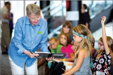  ?? NWA Democrat-Gazette/JASON IVESTER ?? Lois Lowry, two-time Newbery Award winner and author of The Giver and Night of a Thousand Stars, looks over story ideas from Washington Elementary second-grader Sydney Coleman on Wednesday at the Fayettevil­le High School library.