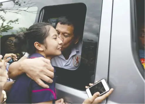  ?? Noel CELIS / AFP / Getty Images ?? Rodrigo Duterte kisses a college student during his 2016 presidenti­al campaign in Dagupan, Philippine­s.
Now, as president, Duterte has signed a new law that clamps down on sexual harassment.