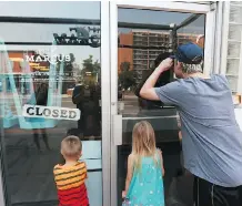  ??  ?? James Davidson, right, joins Airies, 5, and Odin, 31/2, as they look inside the Made by Marcus ice cream gourmet shop. They arrived early.