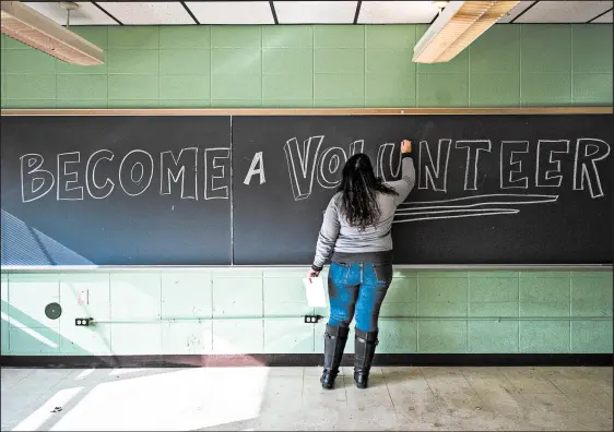  ?? KYLE TELECHAN/POST-TRIBUNE PHOTOS ?? Kelly Massei writes on a chalkboard during a community open house Thursday at the former Garyton School in Portage.