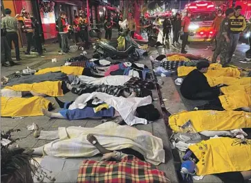  ?? Yelim Lee AFP/Getty Images ?? BODIES are covered on a street in Seoul after the crowd crush. An estimated 100,000 people had gathered in the capital’s Itaewon district for the country’s biggest outdoor Halloween festivitie­s since the pandemic began.