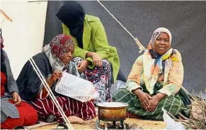  ?? AFP ?? So close, yet so far: Displaced women of Tawergha preparing food at a temporary camp. —