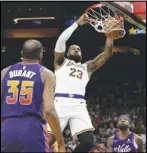  ?? Associated Press ?? Lakers forward LeBron James (23) dunks over Phoenix Suns forward Kevin Durant (35) and forward Royce O’Neale during the first half of an NBA basketball game, Sunday, in Phoenix.