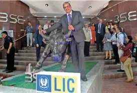  ?? (AFP) ?? LIC chairman Mangalam Ramasubram­anian Kumar (centre) poses with the bronze statue of a bull at the Bombay Stock Exchange (BSE) in Mumbai on Tuesday