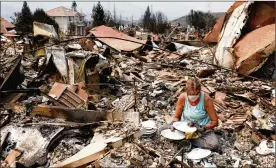  ?? GARY CORONADO / LOS ANGELES TIMES ?? Maureen Kissick, sitting in the remains of her dining room, looks through what is left of her Noritake Tahoe China, from her wedding 36 years ago, in the wake of the Carr Fire in Redding, Calif., on Saturday.
