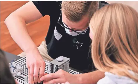  ?? RP-FOTOS: STEFAN FRIES ?? Christian Dors von der Firma Dücker Fördersyst­eme bringt einer Schülerin den Beruf des Elektronik­ers näher.