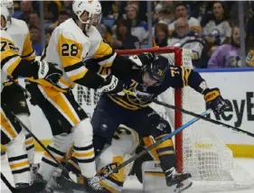  ?? Associated Press ?? Sabres forward Evan Rodrigues, right, is pushed into the net by Penguins defenseman Marcus Pettersson in the third period of the Penguins’ 4-3 loss Friday night in Buffalo.