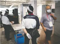  ?? LOIC VENANCE / AFP VIA GETTY IMAGES ?? Security members check journalist­s at the entrance
of the Olympic media centre in Tokyo on Monday.