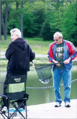  ?? JAMES K. JOSLIN/RIVER VALLEY & OZARK EDITION ?? Retirees Bob Coates, left, and Bob Tunaitis, both of Maumelle, catch and net a rainbow trout at Lake Valencia in Maumelle. The lake is one of the bodies of water in the Arkansas Game and Fish Commission’s Family and Community Fishing Program. That’s...