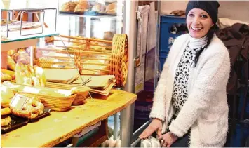  ??  ?? Lächeln gegen das Bibbern: Alexandra Langhans arbeitet im Verkaufsst­and der Bäckerei Laxgang am Moritzplat­z. Sie zieht sich dick an – und wärmt sich an einem kleinen Ofen.