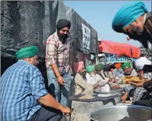  ?? ALTAF QADRI / AP ?? Farmers cook by their vehicles parked on a highway at the DelhiHarya­na state border on Saturday.